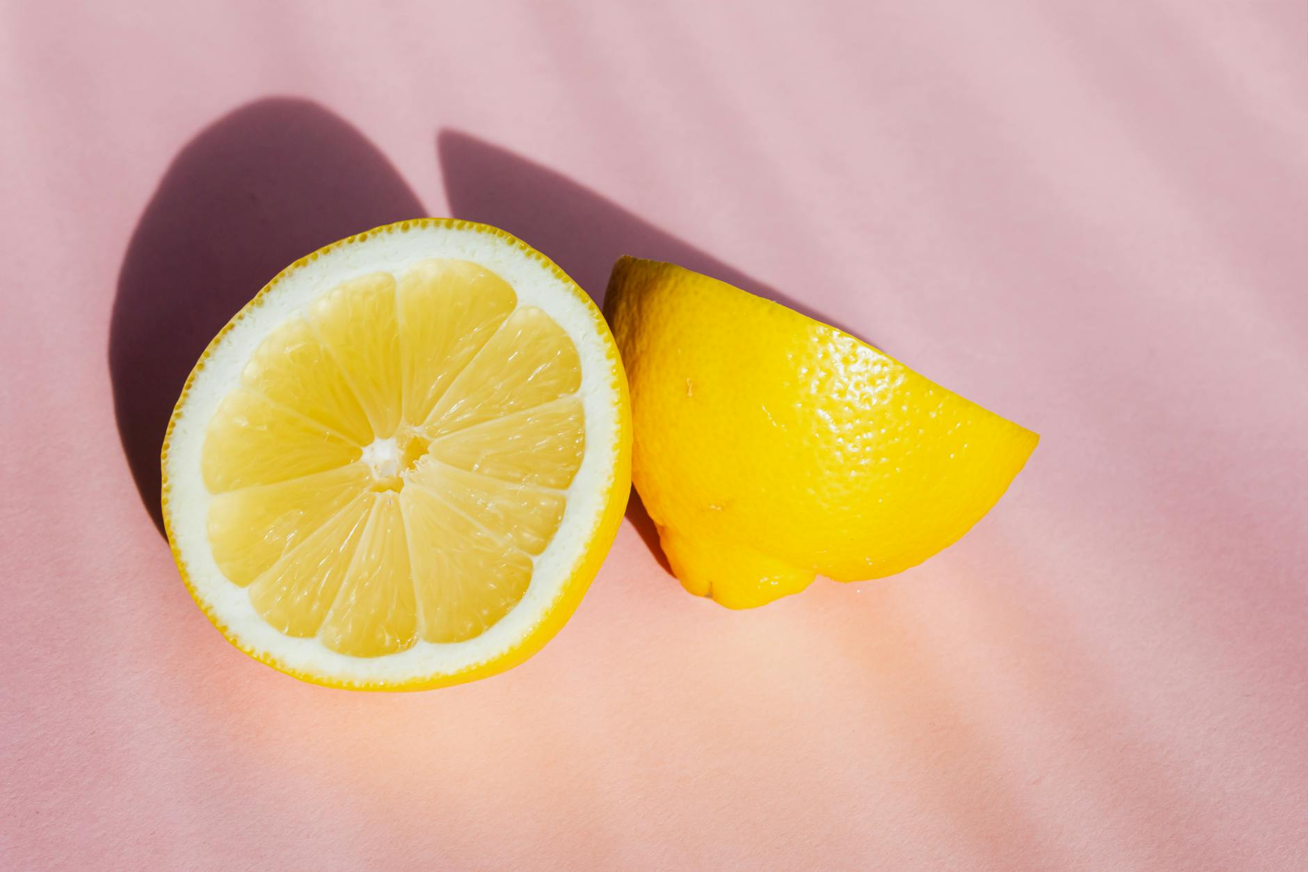 Fresh lemon halves on a pink background in bright sunlight