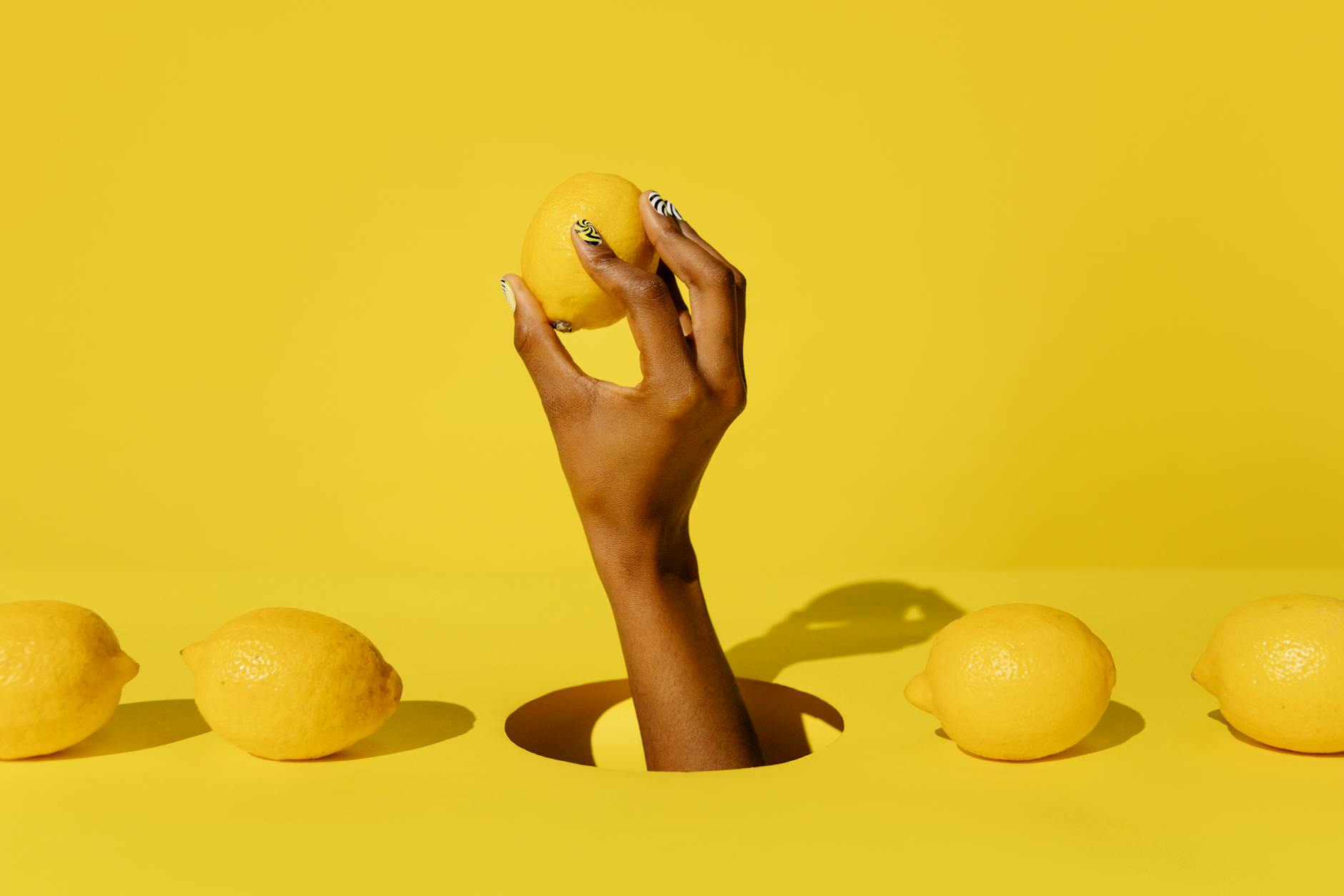 Hand holding a fresh lemon against a yellow background, symbolizing renewal and pleasure recovery
