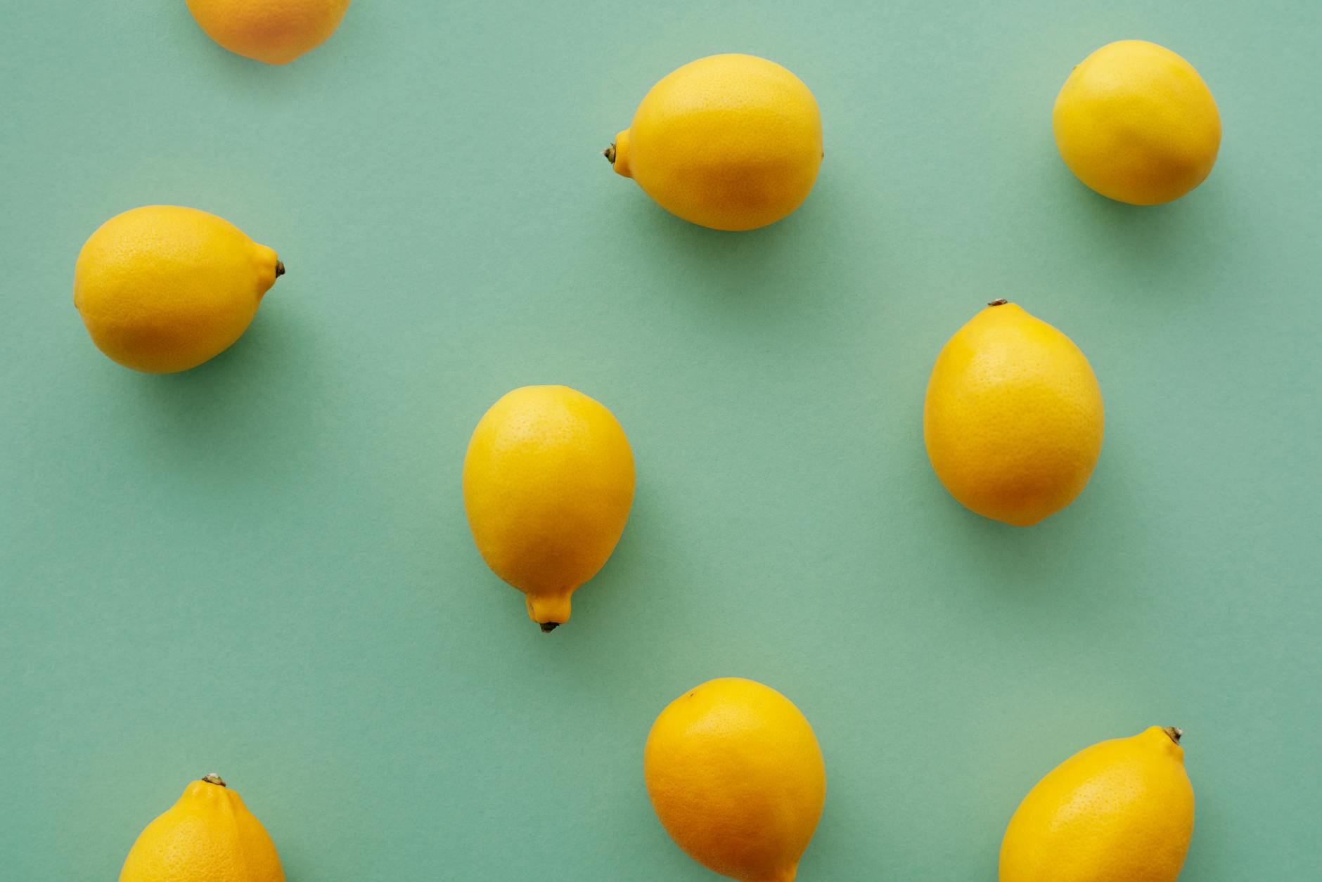 Bright yellow lemons arranged on a pastel green background, symbolizing the refreshing approach to vaginal wellness