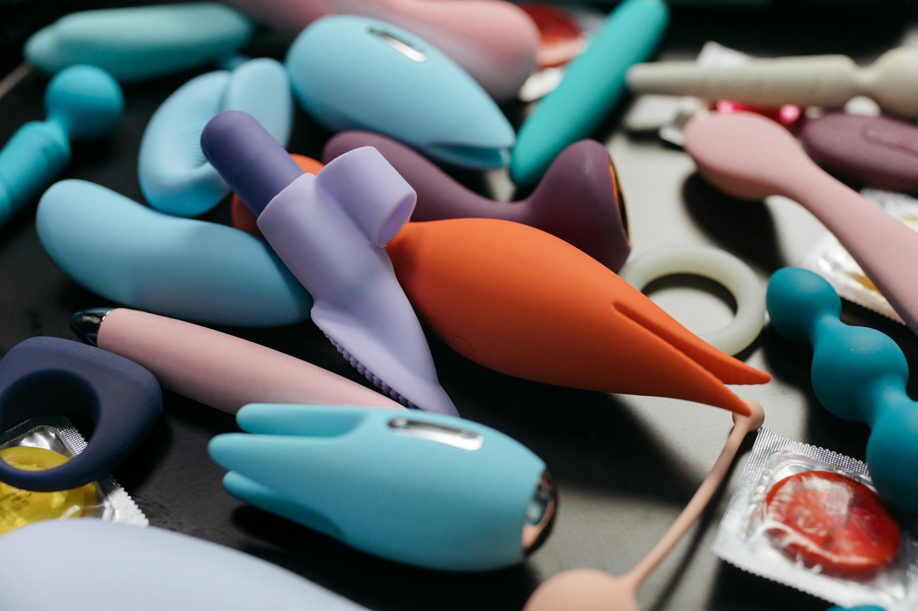 A woman holding a pink clitoral vibrator with art books nearby, emphasizing intimate personal connection