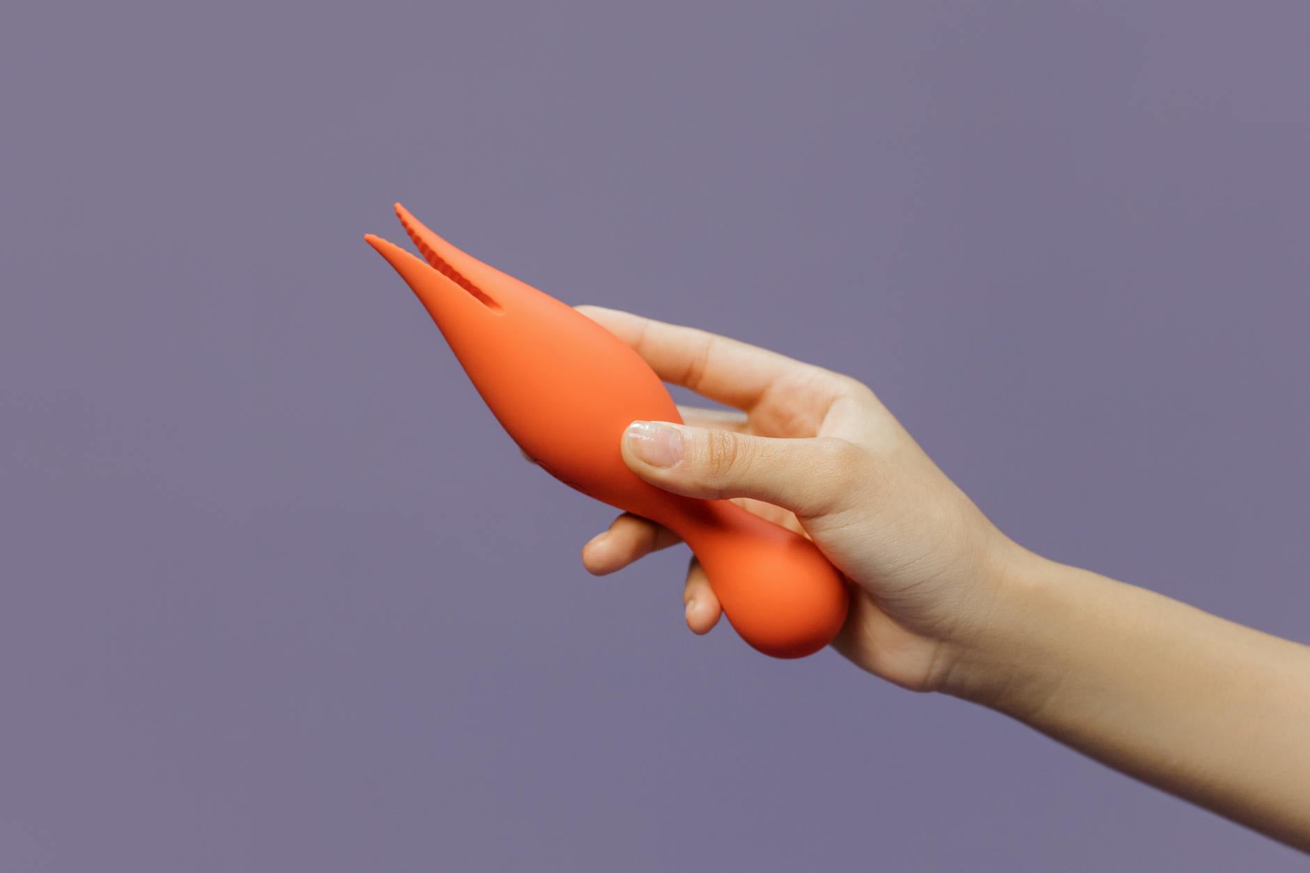 Hand holding a yellow vibrator against a minimalist purple backdrop, showing sensual intention without rush.