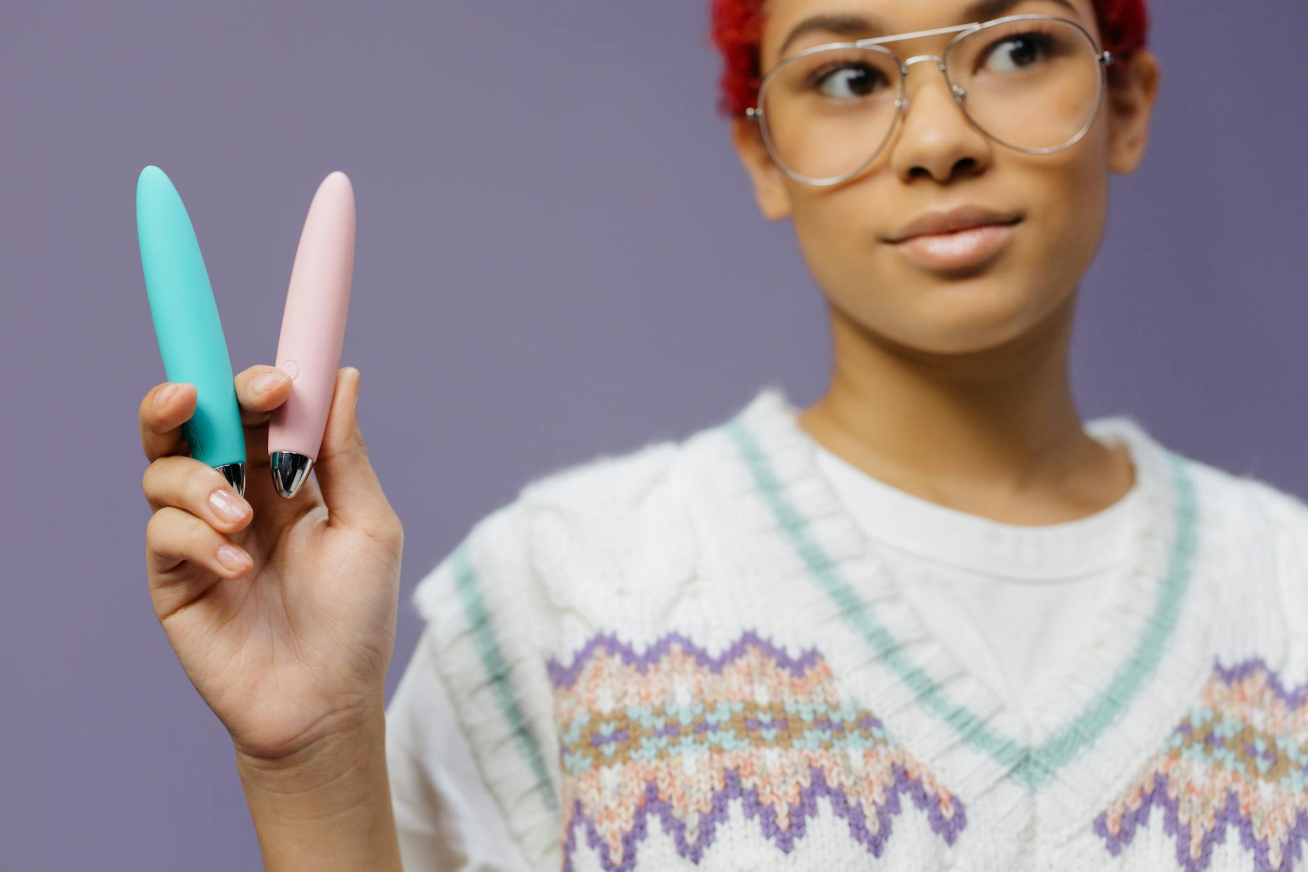 Woman holding colorful lemon vibrators against a purple background, representing renewed pleasure and sensitivity.