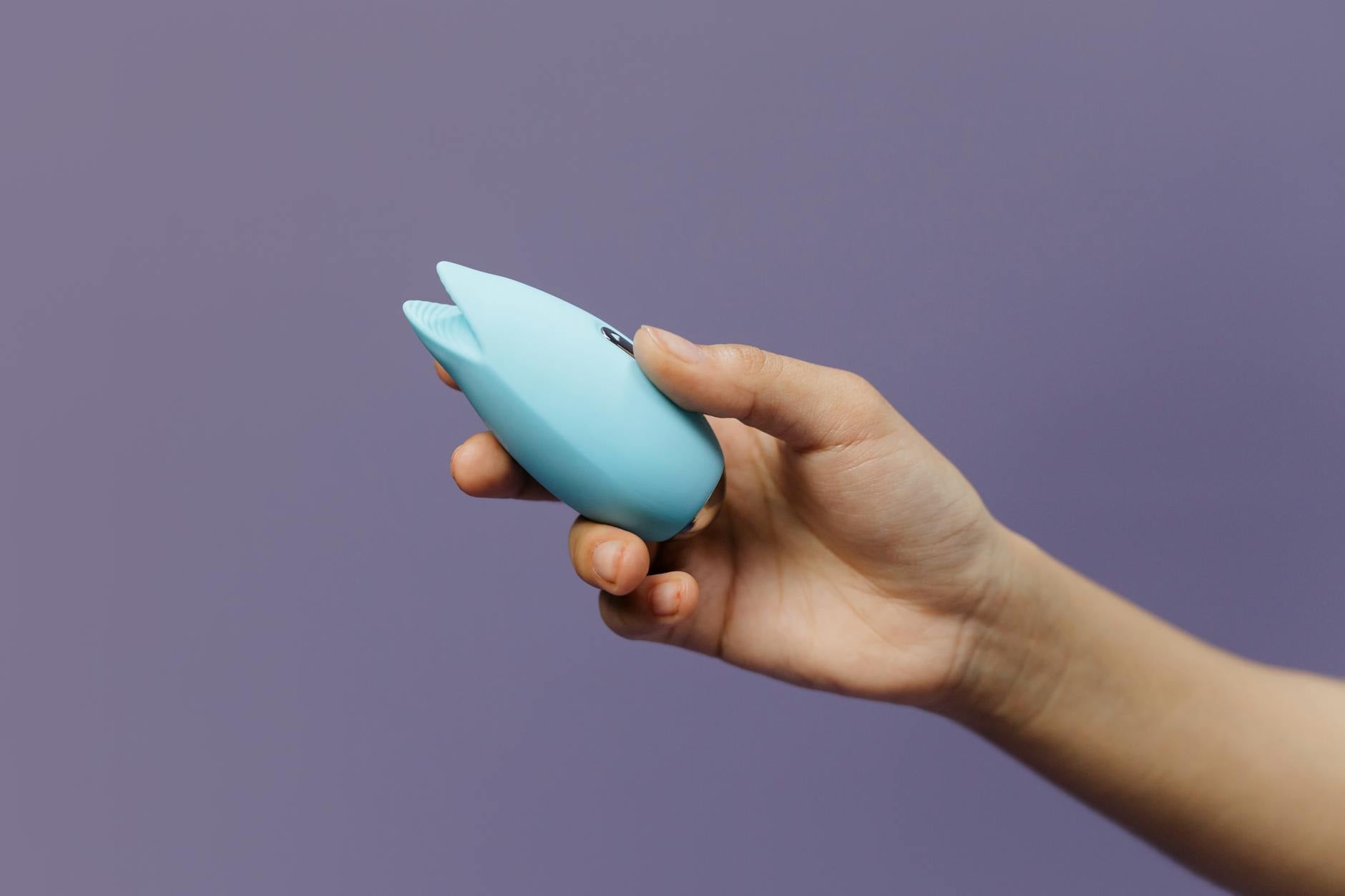 A lemon-colored clitoral vibrator against a purple background, representing intimate self-care during stressful seasons