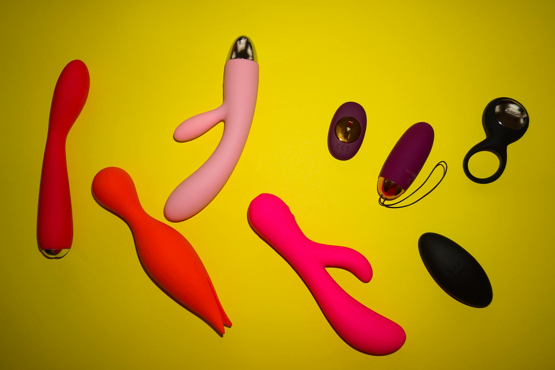 Vibrant arrangement of colorful adult toys on a bright yellow background