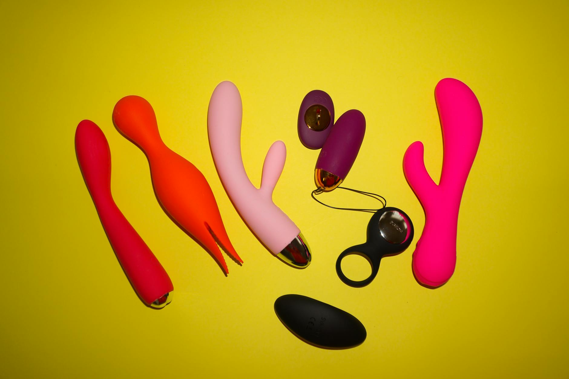 Colorful vibrators arranged on a bright yellow background in a studio setting